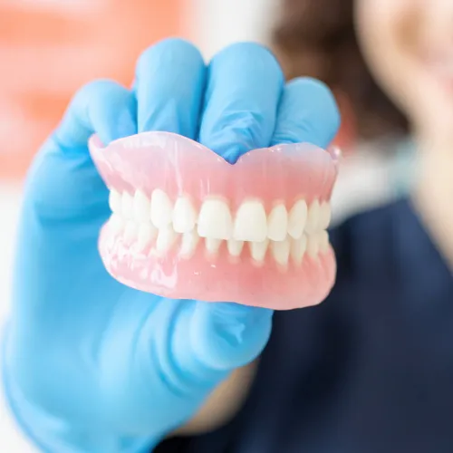 Mano con guante sosteniendo un par de dentaduras.