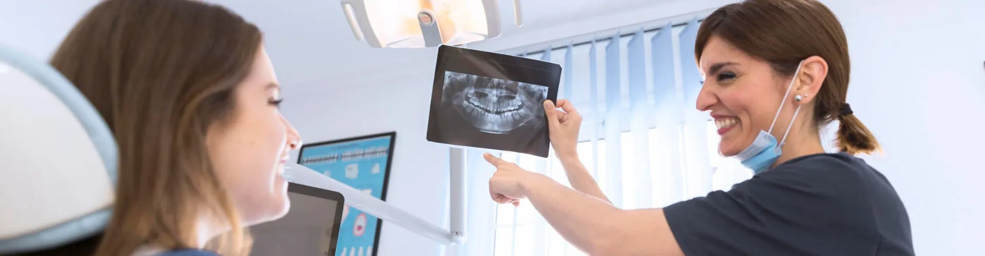 Profesional dental mostrando una radiografía dental a una paciente.
