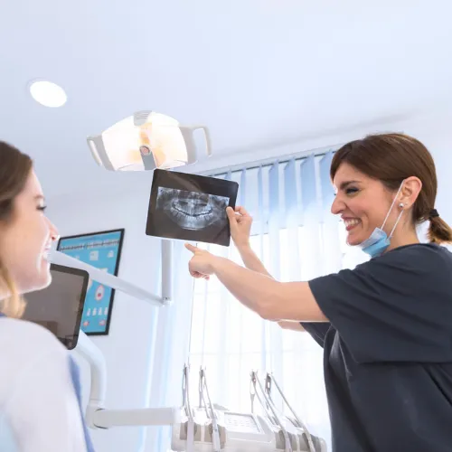 Profesional dental mostrando una radiografía dental a una paciente.