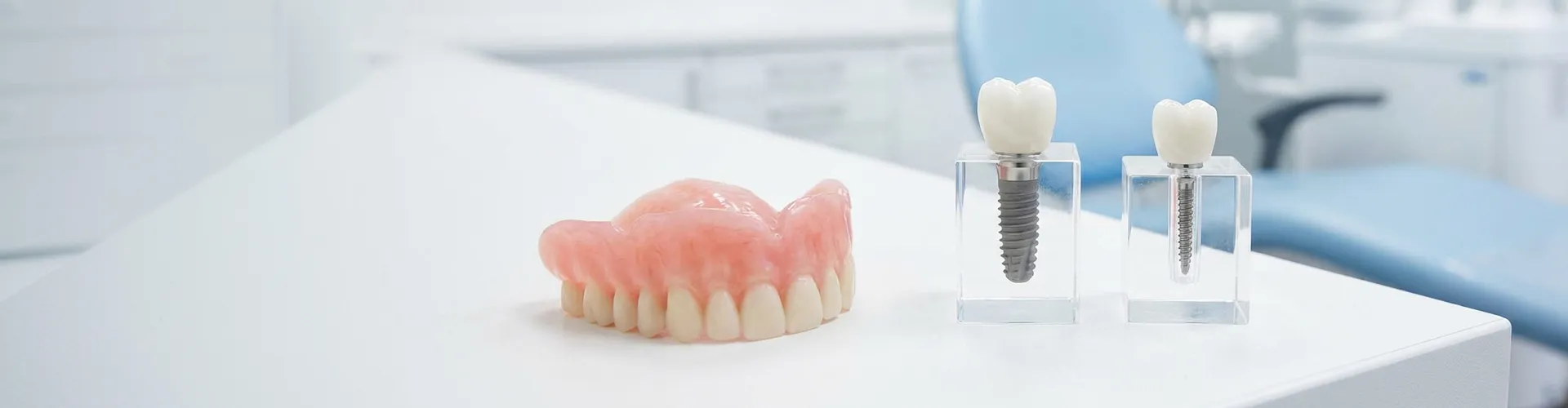 Implante dental junto a mini implante dental sobre superficie blanca.