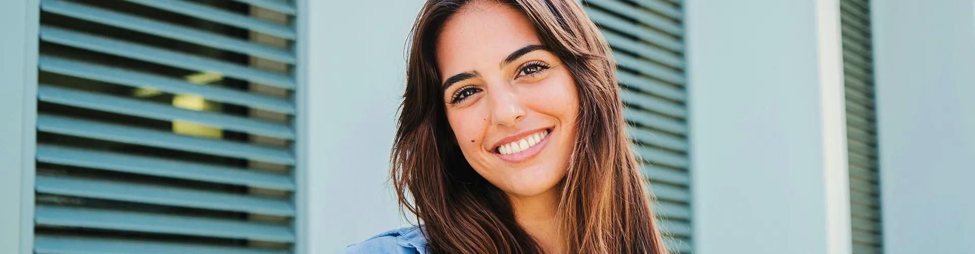 Mujer sonriente de cabello castaño con camisa azul.