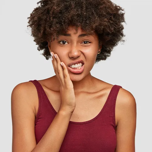 Mujer sujetándose la mejilla con expresión de dolor.