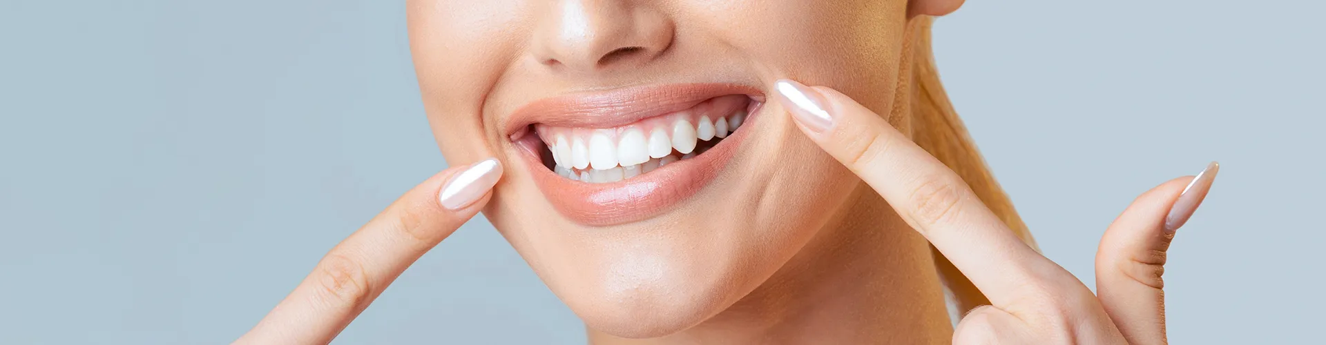 Mujer señalando su sonrisa con ambos dedos índices