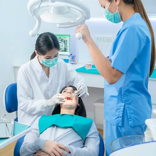 Equipo dental usando herramientas en la boca de un paciente.