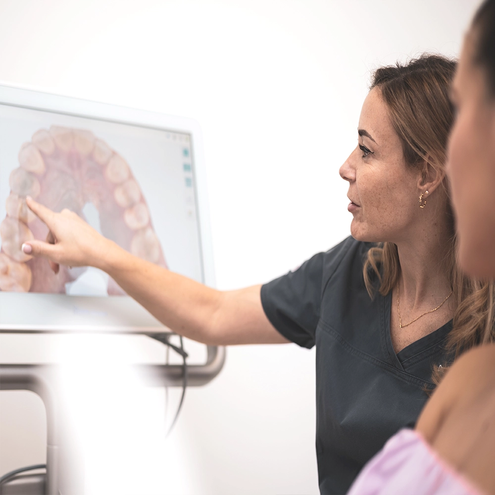 Dentista mostrando información en una pantalla que muestra dientes.