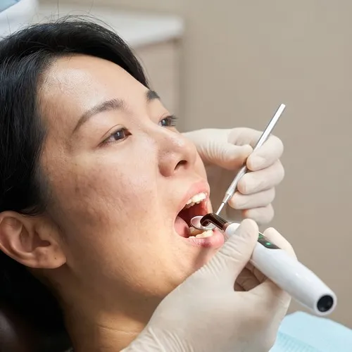 Dentista usando herramientas dentales para examinar a un paciente.
