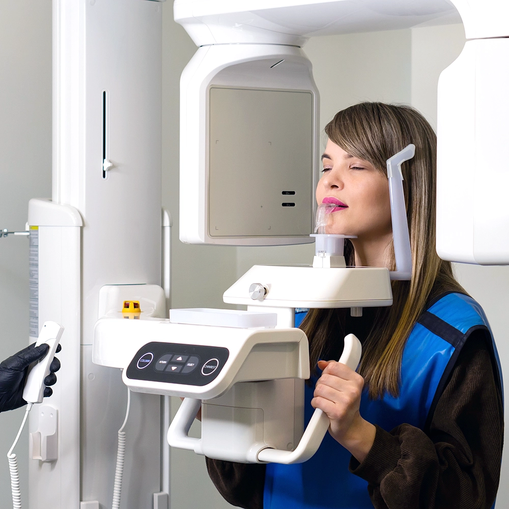 Mujer realizándose una radiografía dental panorámica en una máquina que gira alrededor de su cabeza.
