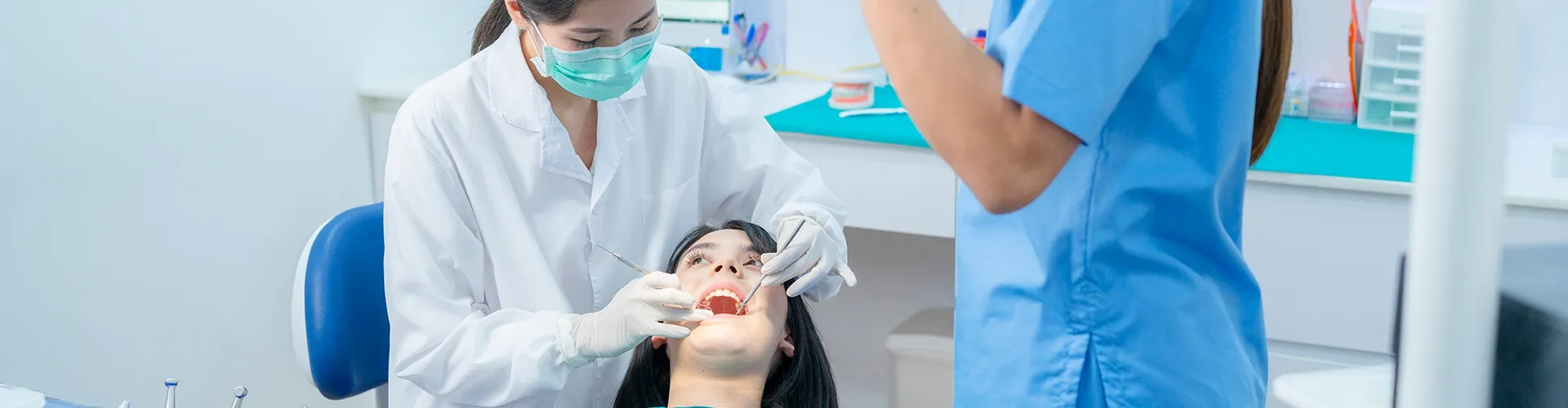 Equipo dental usando herramientas en la boca de un paciente.