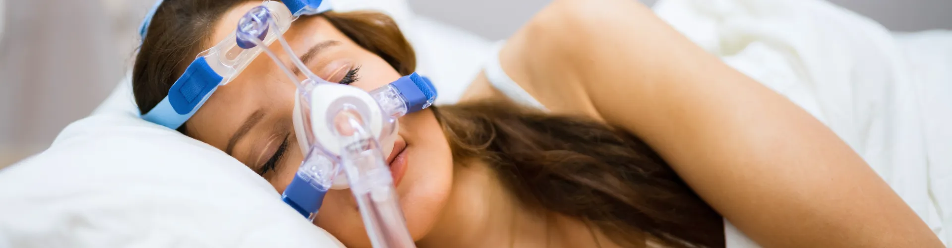 Mujer acostada de lado usando un dispositivo para la apnea del sueño.