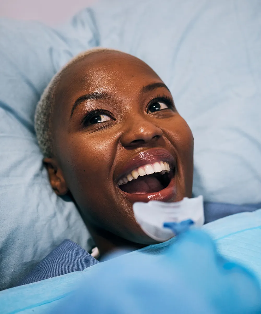 Mujer recostada en el sillón dental, sonriendo.