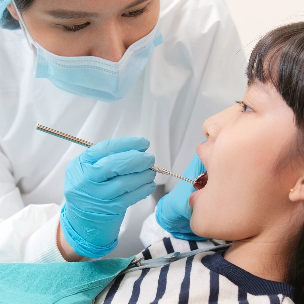 Dentista examinando la boca de un paciente con un espejo dental.