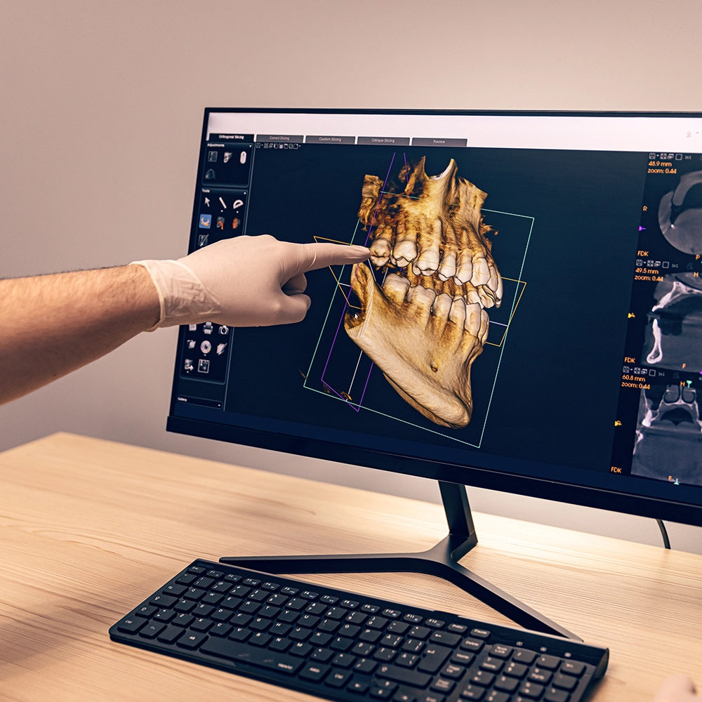 Dentista señalando una pantalla que muestra una imagen 3D completa de una mandíbula con dientes.