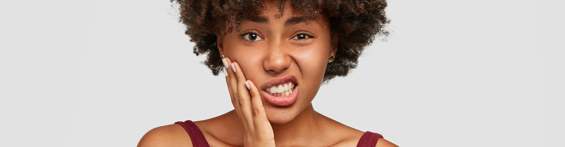 Mujer sujetándose la mejilla con expresión de dolor.