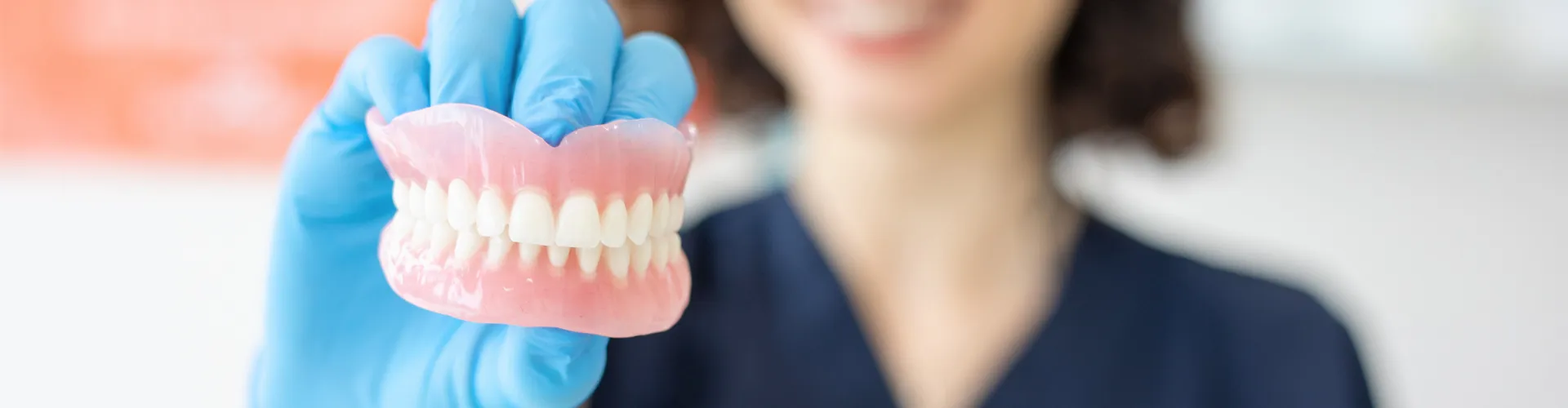 Mano con guante sosteniendo un par de dentaduras.