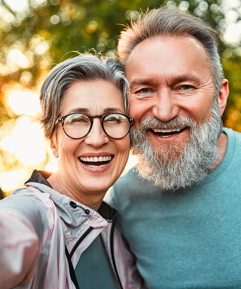 Pareja de personas mayores mirando a la cámara con una sonrisa.